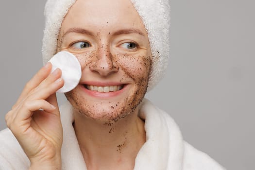 Woman enjoying facial skin care, applying black coffee face scrub, concept of rejuvenation and facial skin care