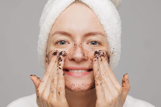 Woman enjoying facial skin care, applying black coffee face scrub, concept of rejuvenation and facial skin care