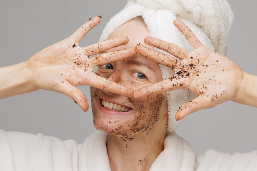Woman enjoying facial skin care, applying black coffee face scrub, concept of rejuvenation and facial skin care
