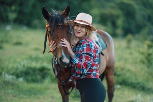 Happy blonde with horse in forest. Woman and a horse walking through the field during the day. Dressed in a plaid shirt and black leggings
