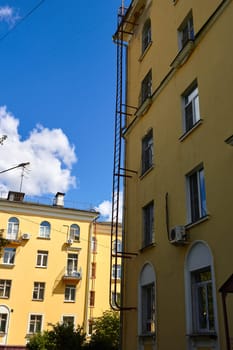 A fragment of the facade of an old multi-storey yellow building on a summer day.