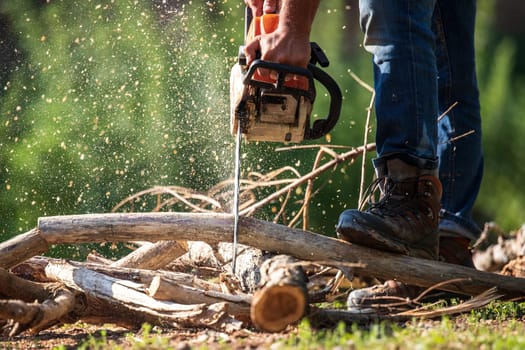 Close-up of process of sawing firewood with chainsaw outdoors, copy space.