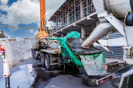 The concrete mixer transports concrete to the concrete pump operator at the construction site, facilitating the pouring of reinforced concrete structures.