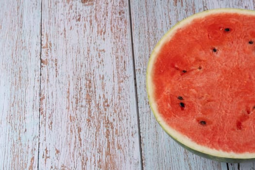 Sliced watermelon on a light wooden table, with copy space for text.