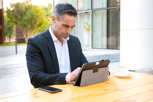 Business on the move: Businessman working on his digital tablet on the street. Man Hands Type On His Laptop Outdoors
