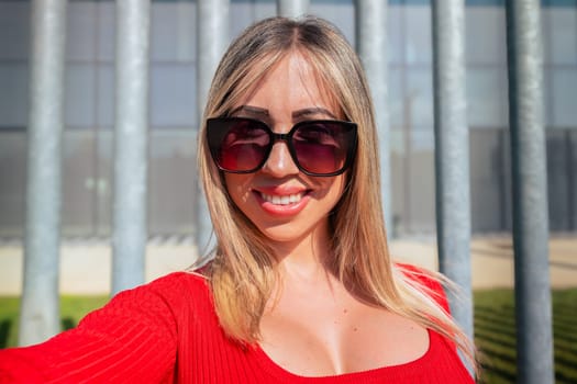 Young woman with sunglasses standing looking surprised and with arms crossed at the camera.