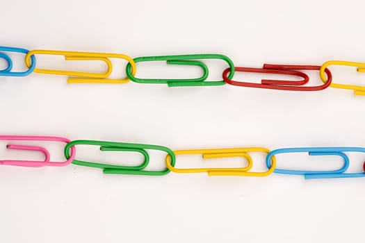 Concept of two links of multi-colored paper clips on white background.