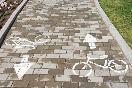 A brick walkway adorned with bicycle and arrow designs, enhancing the urban design with a unique twist. The combination of wood and brickwork creates a rustic yet modern flooring experience
