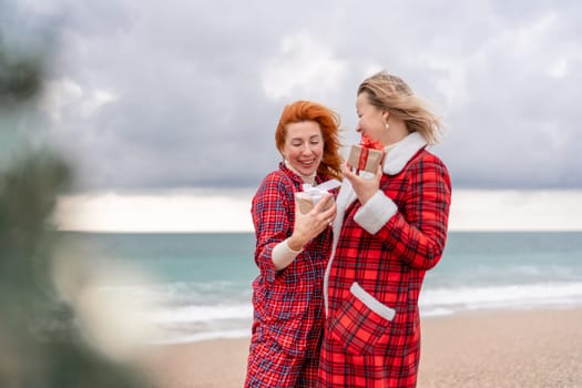 Sea two Lady in plaid shirt with a christmas tree in her hands enjoys beach. Coastal area. Christmas, New Year holidays concep.