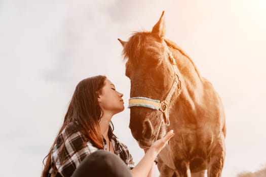 Cute happy young woman with horse. Rider female drives her horse in nature on evening sunset light background. Concept of outdoor riding, sports and recreation.