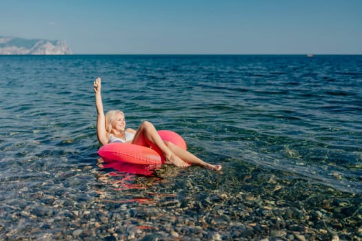 A woman is floating in a red inflatable raft on a body of water. The scene is peaceful and relaxing, with the woman enjoying the moment and the beautiful surroundings