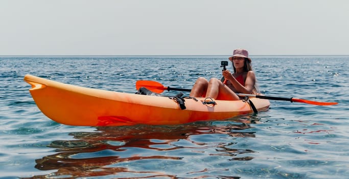 Happy smiling woman in kayak on ocean, paddling with wooden oar. Calm sea water and horizon in background
