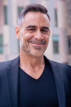 Close-up of a caucasian businessman looking smiling at the camera in a suit standing in outdoor workspace. Front view of a young lawyer with thoughtful expression staring