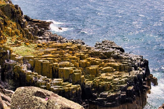 A sizable rock formation situated along the shoreline of a body of water, creating a striking natural landscape that attracts attention