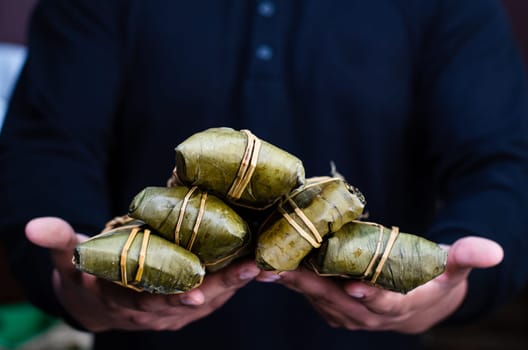 Tamales held by human hands, regional food of Peru