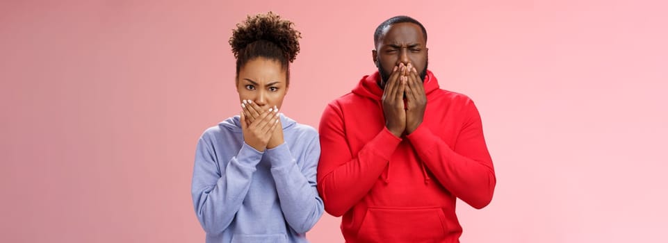 Romantic couple african american boyfriend girlfriend feel sick after eating dinner restaurant press palms mouth frowning wanna puke vomit, standing disgusted shocked pink background.