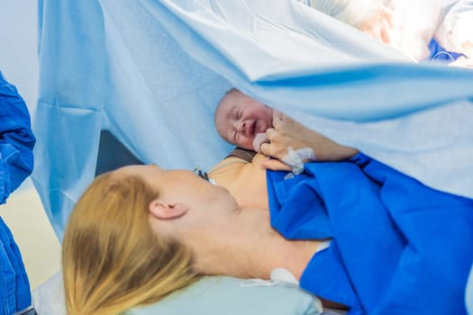 Baby on mother's chest immediately after birth in a hospital. The mother and newborn share a tender moment, emphasizing the bond and emotional connection. The medical staff ensures a safe and caring environment.