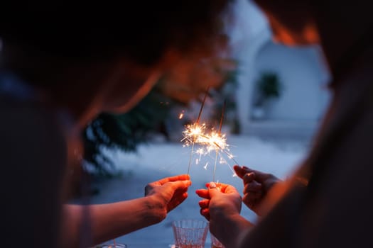 girls celebrating sparklers in hands close up in evening, holiday concept
