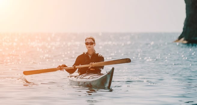 Happy smiling woman in kayak on ocean, paddling with wooden oar. Calm sea water and horizon in background