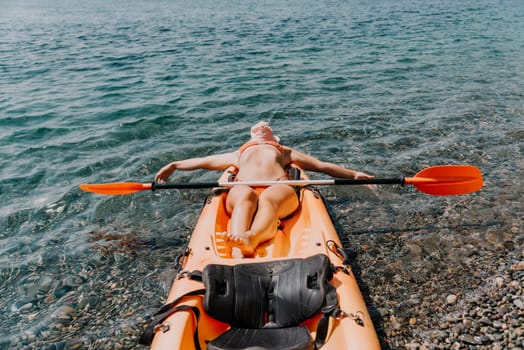 Happy smiling woman in kayak on ocean, paddling with wooden oar. Calm sea water and horizon in background