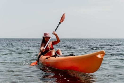 Happy smiling woman in kayak on ocean, paddling with wooden oar. Calm sea water and horizon in background
