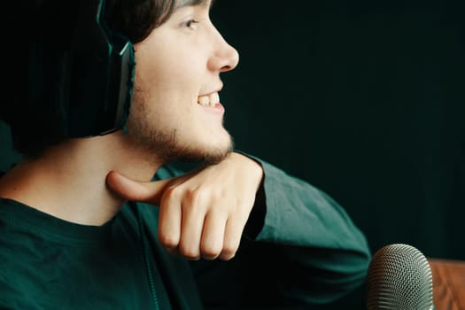 A young man, smiling, poses thoughtfully with a microphone and headphones, proudly showcasing his creativity