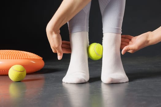 Strengthening the ankle joint with a tennis ball, a therapist is treating the legs, a close-up foot massage