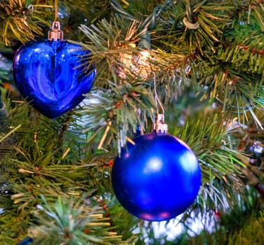 Blue heart and blue bauble on pine tree brenches. Closeup look of Christmas decorations