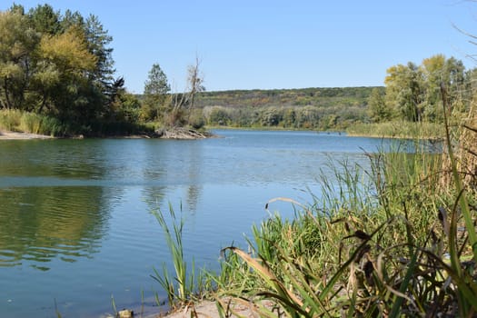 Forest lake in the autumn afternoon. Calm water with reflection of trees. Attractive morning view of Lake. Clear fresh nature, untouched. Forest in the background. National reserve