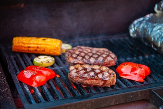 Beef steaks with vegetables on the grill with flames