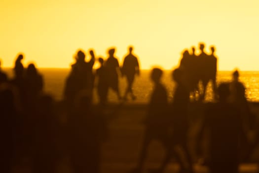 Silhouettes of people at yellow bright sunset. Mid shot