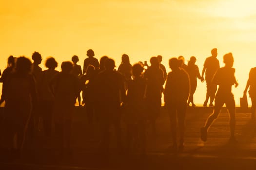 A crowd of young people at a bright sunset. Mid shot