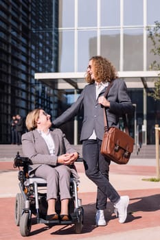 business man and woman using wheelchair smiling happy while talking outdoors at financial district, concept of diversity and urban lifestyle, copy space for text