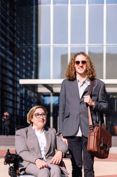 business man and woman using wheelchair smiling happy looking at camera outdoors at financial district, concept of diversity and urban lifestyle, copy space for text