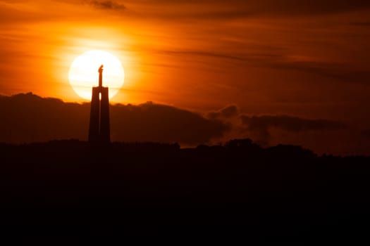 Statue of Jesus Christ at bright orange sunset. Mid shot