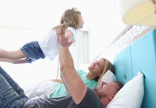 Dad is holding child in outstretched arms above him. Plane games with a child in concept