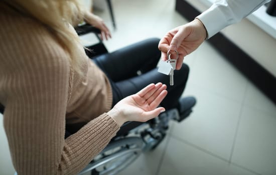 Woman in wheelchair is given keys to house. Getting social housing for disabled people concept