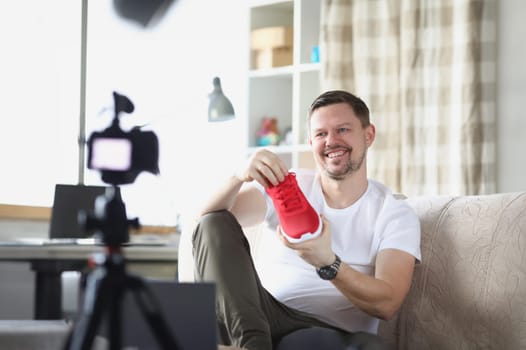 Smiling man demonstrates sneaker on video camera. Introducing new product blog concept