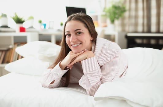 Portrait of smiling woman on a white bed. Choosing right mattress for sleeping concept
