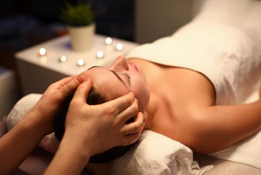 Woman is given rejuvenating facial massage in an aroma room. Relaxing facial massage techniques concept