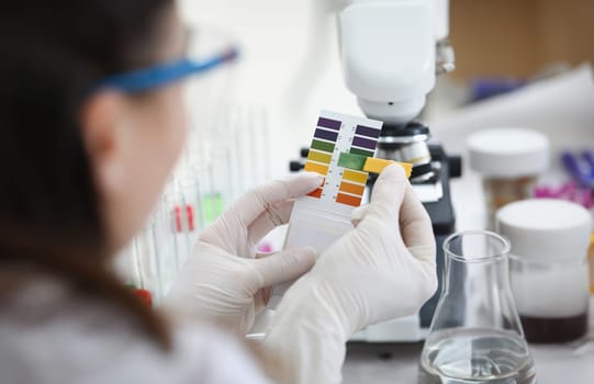 Researcher holds Ph test strip for research. Chemical composition of matter concept