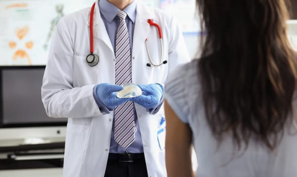 Pastic surgeon demonstrates a silicone implant to patient. Breast augmentation surgery concept