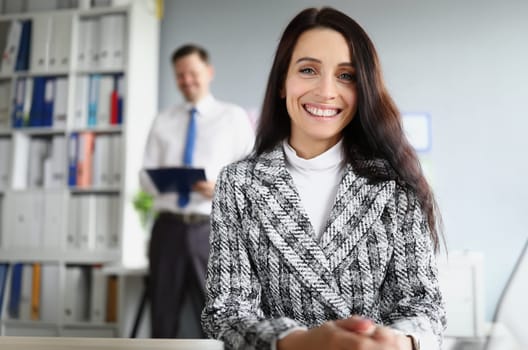 Portrait of smiling brunette woman in workplace behind her is businesswoman. Small and medium business development concept