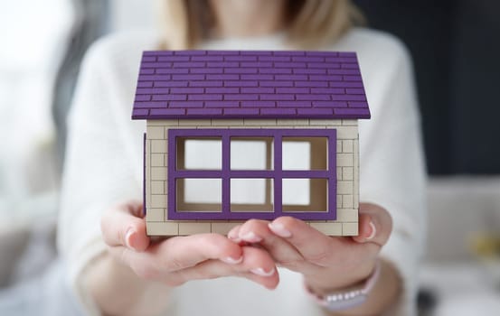 Woman holding toy wooden house in her hands. Home insurance concept