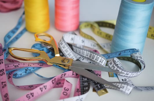 Seamstress scissors and tape measure lying in workshop closeup. Small business development concept