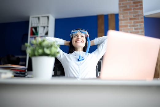 Woman in diving mask dreaming of sea at workplace. Rest during pandemic concept