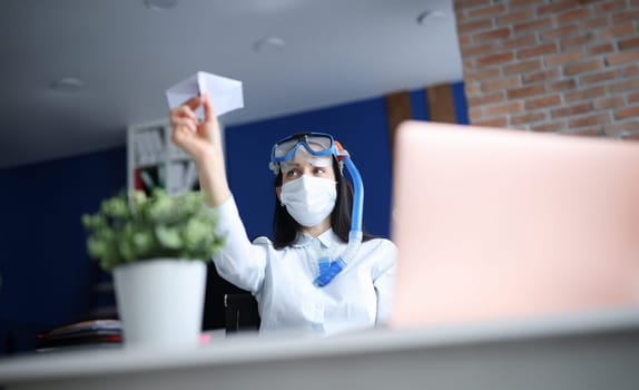 Woman in medical facemask and diving mask launching paper plane. Closed borders during pandemic covid-19 concept