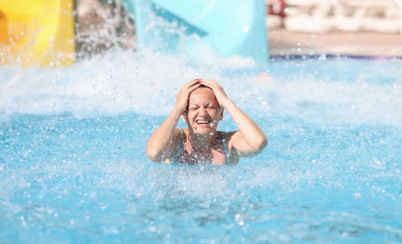 Portrait of woman who has driven down slide in water park. Fun in the water park for adults concept