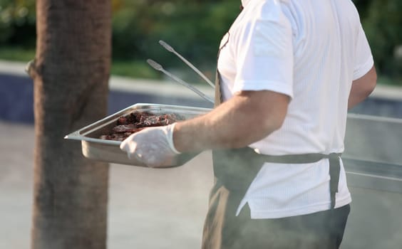 Cook carries baking sheet with grilled meat. Kebab recipes concept