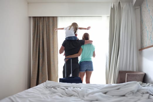 Family with child are looking out window in hotel room. Best places for family travel concept